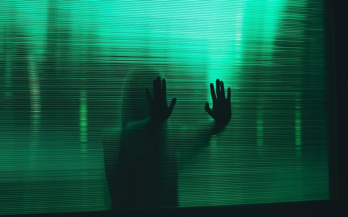 Girl with hands pressed against green glass